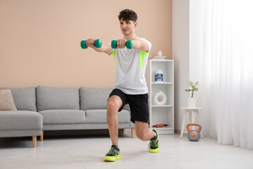 Young man training with dumbbells at home