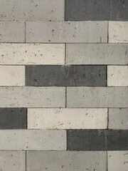 Close up of monochrome black, grey, and white flattened brick wall, exposed and weathered. Seamless background texture.