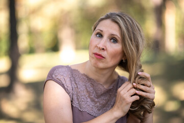 Portrait of a beautiful blonde young girl in a summer city park.