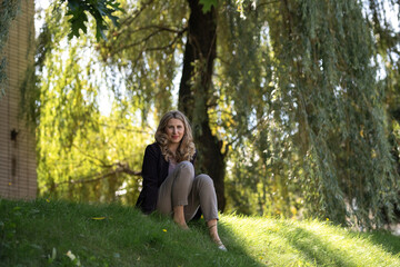 Portrait of a beautiful blonde young girl in a summer city park.