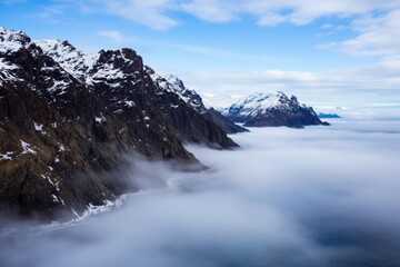 Obraz premium Landscape Of The Coastline And Rugged, Snow Covered Mountains Under A Blue Cloudy Sky