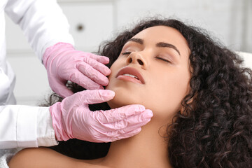 Fototapeta premium Beautiful young African-American woman receiving facial massage in beauty salon, closeup