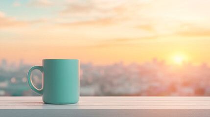 A teal mug sits on a white surface against a blurry backdrop of a city sunrise. Warm, peaceful morning vibes.