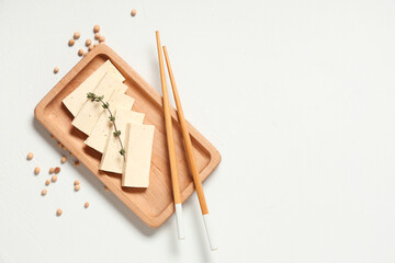 Tray with slices of tasty tofu cheese, chopsticks and chickpeas on white background