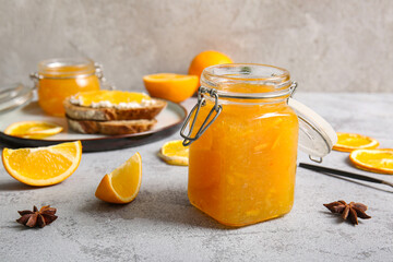 Jar of sweet orange jam and star anise on grey background