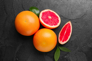 Fresh ripe grapefruits and leaves on black background