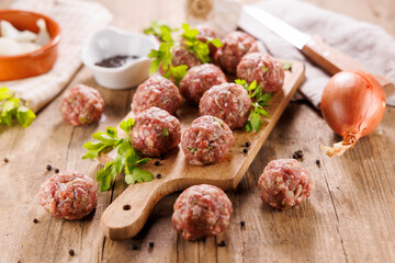 raw meatballs with parsley on wooden board