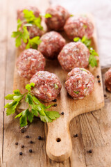 raw meatballs with parsley on wooden board