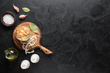 Glass jar with homemade sauerkraut, salt and bottle of oil on black background. Top view