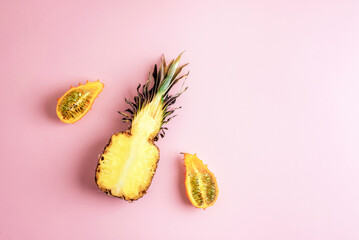 Pineapple and kiwano fruit arranged creatively on a pastel pink background. Top view, flat lay, copy space