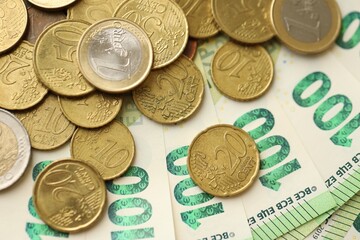 Big amount of euro cent coins lies on hundred euro bills banknotes