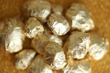 Small pile of golden nuggets on shiny gold glitter background