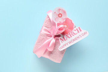 Festive postcard with gift box on blue background. Happy Women's Day