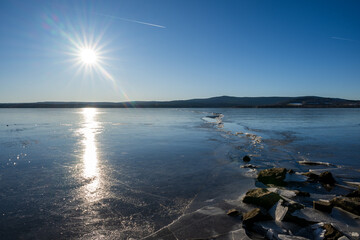 Winter sunny day at a frozen lake with ice floes