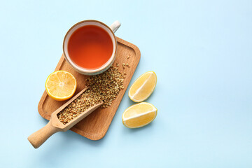 Cup of hot buckwheat tea with lemon on blue background