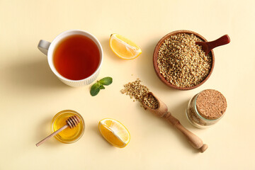 Cup of hot buckwheat tea with lemon and bowl of honey on yellow background