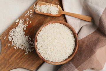 Bowl and wooden scoop with raw rice on white background