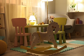 Obraz premium Interior of children's room with table, toys and glowing lamps at night