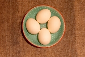 Fresh eggs arranged on a decorative plate set on a wooden table for a rustic kitchen aesthetic