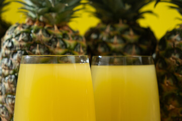 Pineapple juice in glasses among fresh pineapples.