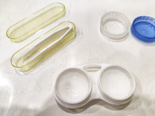 Assorted contact lenses cases and tools displayed on a flat surface in a bright room