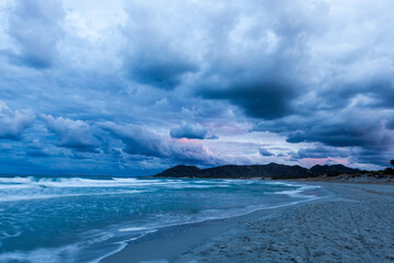 Mediterranean sea on stormy weather in Sardinia, Italy. Sardinian coast with dark cloudy sky at sunset near Capo Comino, Siniscola comune.