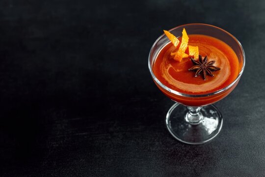 Topaz-inspired cocktail with red wine float and orange peel twist served in crystal glass
