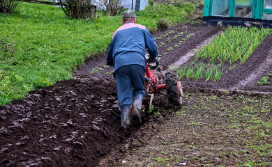 Tractor plowing field in rural area, preparing soil for planting season