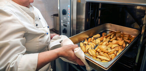Chef prepares golden-brown roasted potatoes in a commercial kitchen setting