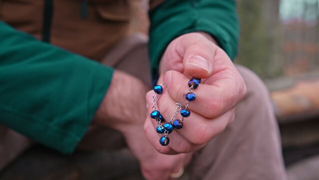 Caucasian Male Praying on Rosary Beads during Outdoor Hiking Trip