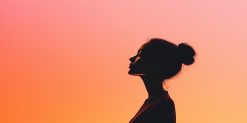A woman is standing in front of a pink sky. She is wearing a red shirt and has her hair in a bun. Concept of calmness and serenity, as the woman is lost in thought