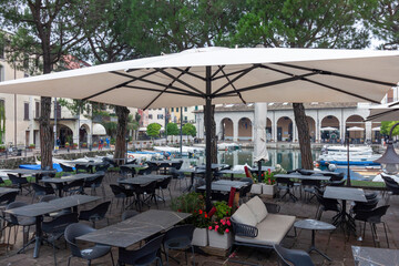 An outdoor dining area in Desenzano del Garda, featuring tables and chairs under large umbrellas