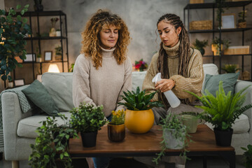 two female friends plant flowers together take care of home plants