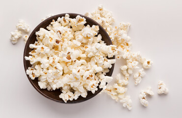 Wooden rustic bowl of popcorn isolated on white background, top view. Fast food, cinema snack and entertainment concept, cutout