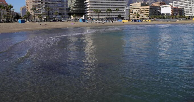 Slow motion footage of the beautiful beach in the town of Fuengirola, Malaga, Spain showing the beach known locally as Playa de los Boliches and hotels and apartments on the beach front