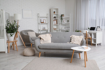 Interior of modern living room with grey sofa and books on coffee table