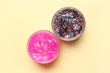 Jars of glitter on beige background, closeup
