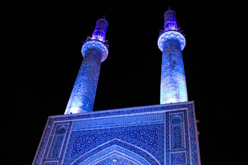 The Jāmeh aka jame Mosque of Yazd beautiful persian architecture with mosaic tile work ceramic geometric shapes minarets islamic architecture at night 