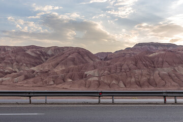 road in the desert with clay mountains in the back during sunset with beautiful clouds in iran 