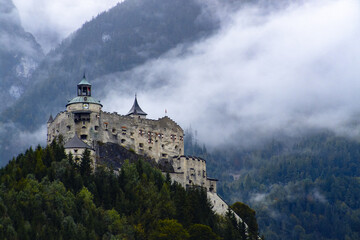 Naklejka premium The mighty Hohenwerfen Fortress, located in the Austrian Alps, rises above forests and mountains. Its medieval architecture and picturesque landscape make it an iconic historical and tourist attractio