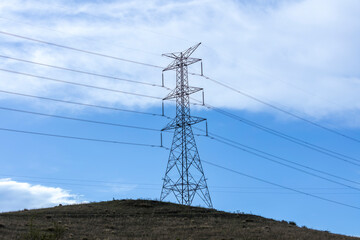 Photograph of a large steel electricity Transmission Tower on a grassy hill in regional Australia.
