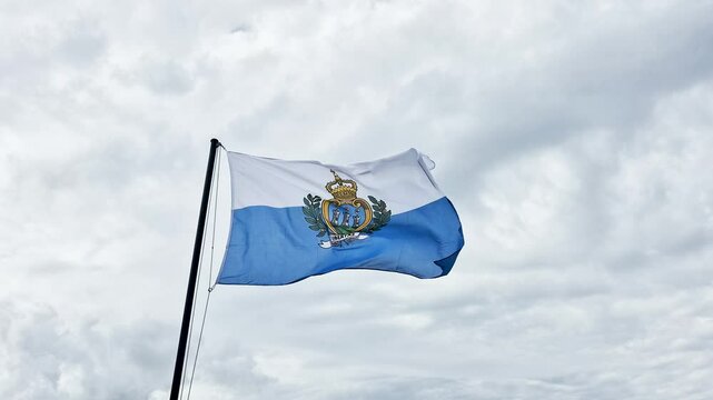 Flag of San Marino with clouds in background.