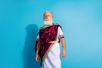 Photo of handsome senior male strict face wear ancient greek god king dress isolated on blue color background