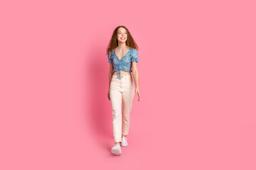 Happy young woman walking on a pink background smiling confidently