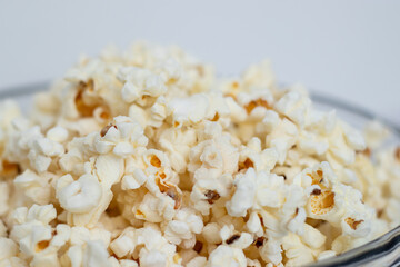 Close up of tasty popcorn in a glass bowl on white table background 
