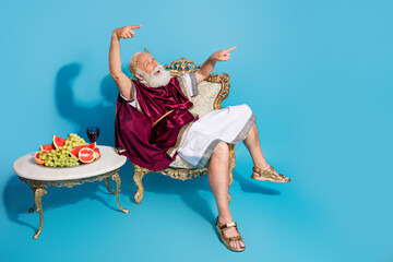 Photo of man actor dressed as ancient mythological personage looking empty space isolated on blue...