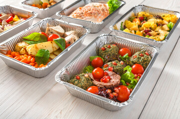 Healthy food background. Take away of natural organic meals in foil boxes. Fitness nutrition, meat, fresh salads, fruits and vegetables. Restaurant dishes delivery