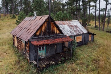 Abandoned cabins in a wooded area. Decaying wooden structures and weathered metal roofs. Nature reclaiming the property. , Deadwood, South Dakota, USA.