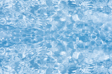 Blue water with ripples on the surface. Defocus blurred transparent blue colored clear calm water surface texture with splashes and bubbles. Water waves with shining pattern texture background.