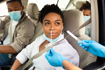 Covid-19 Diagnostic. Black Family Of Three Getting Tested For Coronavirus With Nasal PCR Test Sitting In Automobile, Wearing Protective Face Masks. Covid Pandemic Outbreak Concept